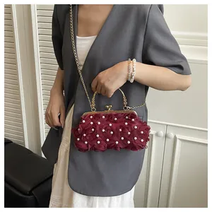 Detail of burgundy evening clutch with floral rose 3D texture and white pearl accents