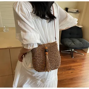 Detailed view of woven straw bag featuring long fringe and decorative wooden beads