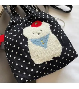 Détail du sac noir à pois avec broderie en relief d'un ours en peluche doux