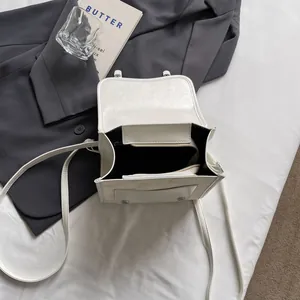 Minimalist white leather messenger bag with flap closure and magnetic pockets for women