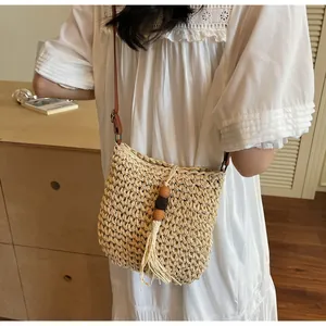 Detail of hand-woven straw bag featuring beige texture, wooden beads, and fringe tassel