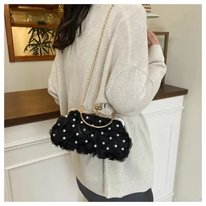 Detail of black floral evening bag with white pearl accents and golden metal hardware