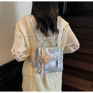 Fashionable silver metallic backpack with bow clasp and bear charm on back view
