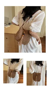Detail of woven straw shoulder bag featuring decorative tassels and wooden beads