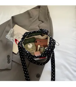 Intérieur spacieux d'un sac seau noir à pois montrant le rangement de cosmétiques