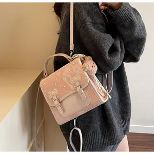 Detail of pink faux leather handbag with rhinestone accents and cute bear charm