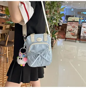 Detail of light blue crossbody bag with bow-shaped pocket and cute plush toy keychain