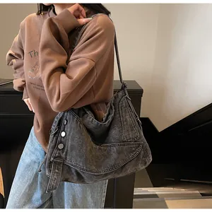 Dettaglio della borsa tote in denim vintage con fibbie metalliche e tracolla larga