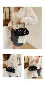 Detailed view of black evening clutch with fabric roses, pearls, and gold chain strap