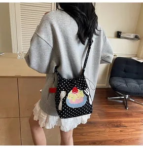 Sac bandoulière en toile noire à pois blancs et broderie porté par un mannequin
