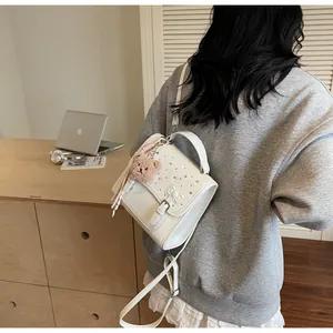 White PU leather bag with bow and teddy bear charm shown on a casual model