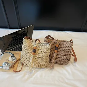 Minimalist woven straw crossbody beach bag with tassel and leather strap in soft cream