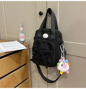 Close-up of black crossbody bag with bow detail and heart charm in home setting