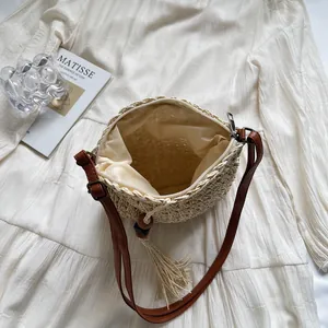 Fashionable woven round beach bag with brown leather strap and decorative tassel