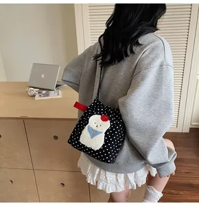 Vue détaillée d'un sac bandoulière en toile à pois noirs avec broderie de chiot en peluche