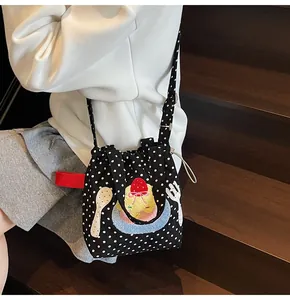 Détail du sac seau noir à pois avec broderie dessert et ruban rouge sur le côté