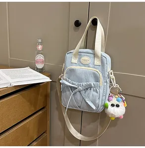 Close-up of light blue canvas handbag with a bow detail and plush pendant accessory