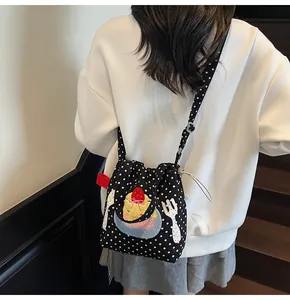 Détail d'un sac bandoulière en toile à pois noirs avec broderie de dessert colorée