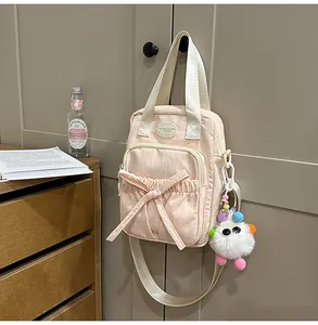 Detail of pink canvas mini bag with bow decoration and cute plush monster charm