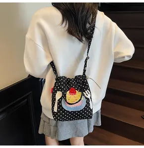Détail du sac bandoulière en toile à pois avec broderie cupcake sur le dos du mannequin