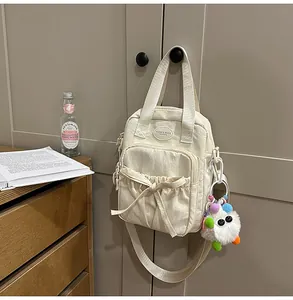 Detail view of cream canvas handbag with bow pocket and cute plush mascot charm