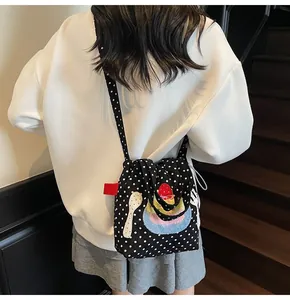 Sac bandoulière en toile à pois avec broderie fraise porté par un mannequin en style décontracté