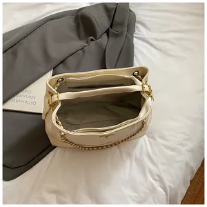 Minimalist off-white leather tote bag with interior compartments and gold chain detail