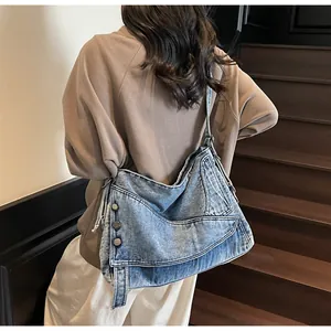 Dettaglio della borsa a tracolla in denim blu con bottoni metallici e trama lavata