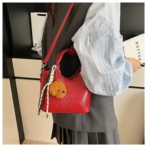 Rote Bucket Bag mit Teddybär-Anhänger und Seidenschal-Detail getragen vom Model