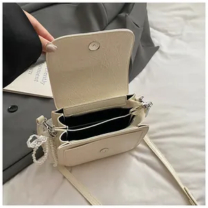 Detail of cream crossbody bag interior with dual compartments and pearl lace charm