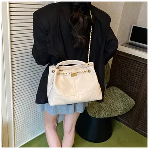 Detail of beige quilted shoulder bag with gold chain and metal lock worn by a model