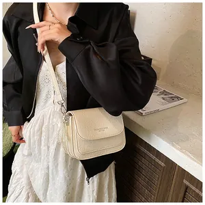 Detail of off-white crossbody bag with pleated texture and pearl pendant decoration