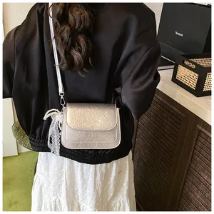 Detail of silver pleated crossbody bag with pearl and lace charm shown on a model
