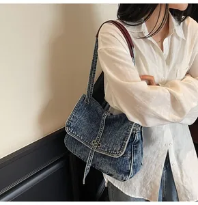 Detail of vintage denim shoulder bag featuring washed blue fabric and silver buckle