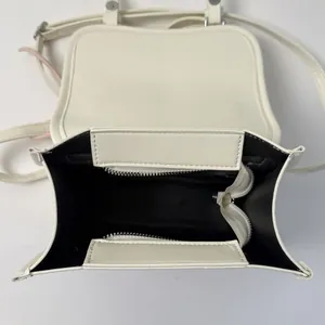 Internal view of a mini checkered crossbody bag showing black lining and white zipper compartment