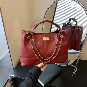 Quilted wine red tote bag with gold buckle and chain strap shown in mirror reflection