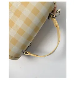 Detailed close-up of yellow gingham mini backpack with faux leather handles and metal rings