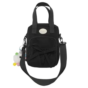 Black nylon handbag for women with bow detail, logo patch, and unicorn charm accessory