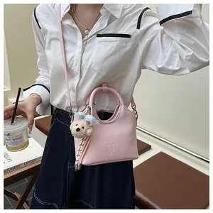Detail der rosa Bucket Bag aus genarbtem Leder mit süßem Teddybär-Anhänger und Schleife
