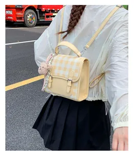 Close-up of yellow checkered mini backpack featuring a plush bear charm and ribbon detail