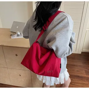 Detail of red nylon crossbody bag featuring BNT embroidery and adjustable strap