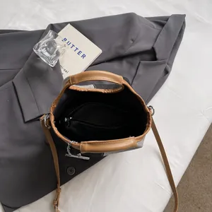 Chic grey canvas bucket bag with brown leather trim and chain detail, top view