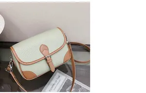 Detail of lychee pattern leather crossbody bag with silver buckles on a wooden table