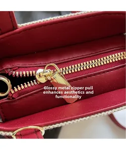 Macro view of smooth golden metal zipper pull on red denim handbag with woven trim