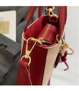 Detail of red leather and beige canvas tote with gold D-ring hook and zipper closure