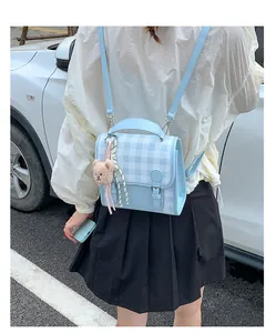 Outdoor shot of a mini blue checkered backpack with a cute plush bear charm detail