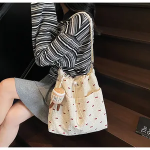 Detail of a large mesh drawstring shoulder bag with red bows and a cute plush charm