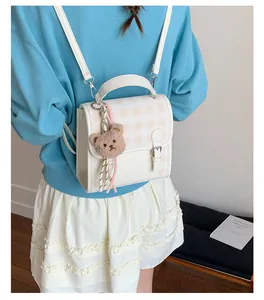 Detailed view of mini checkered backpack with plush bear charm and adjustable straps