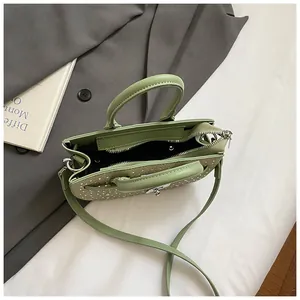 Detail view of mint green leather saddle bag with silver hardware and black lining