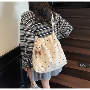 Rear view of floral drawstring shoulder bag with bow embroidery and coffee cup plush charm